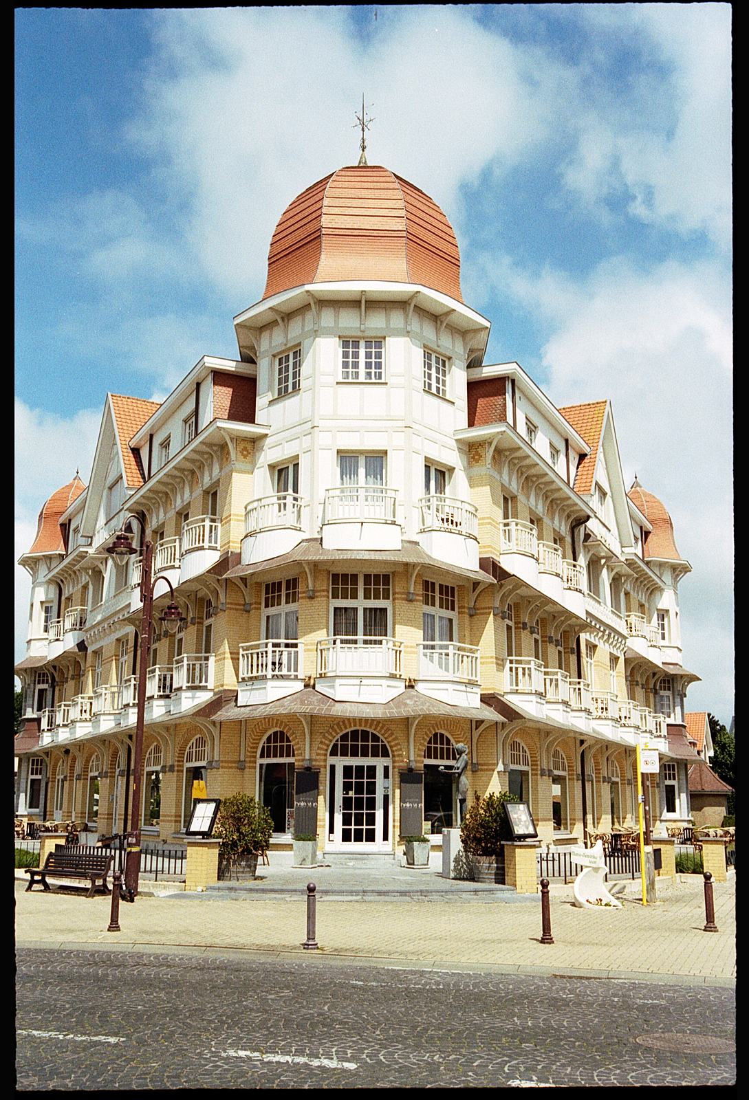 Vue d'un bâtiment élégant à De Haan, en Belgique, avec une architecture de style belle époque, featuring un dôme en tôle cuivrée.