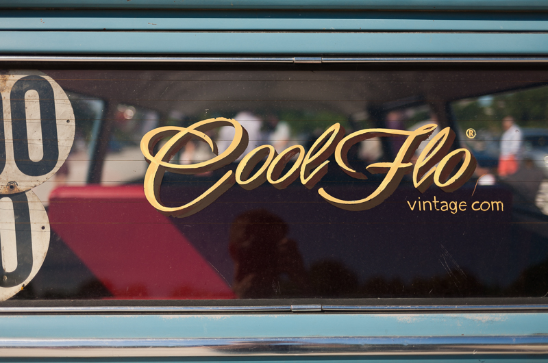 Vue rapprochée d'un autocollant vintage sur une vitre, affichant le texte 'Cool Flo vintage.com' dans une police stylisée, sur fond bleu.