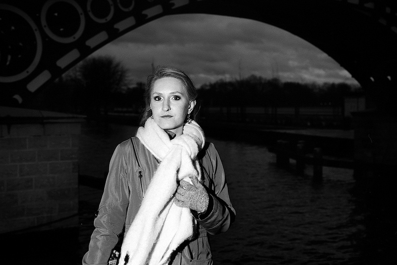 Femme posant avec une écharpe blanche sur le pont Napoléon pendant un shooting photo nocturne en noir et blanc, avec un éclairage de flash.