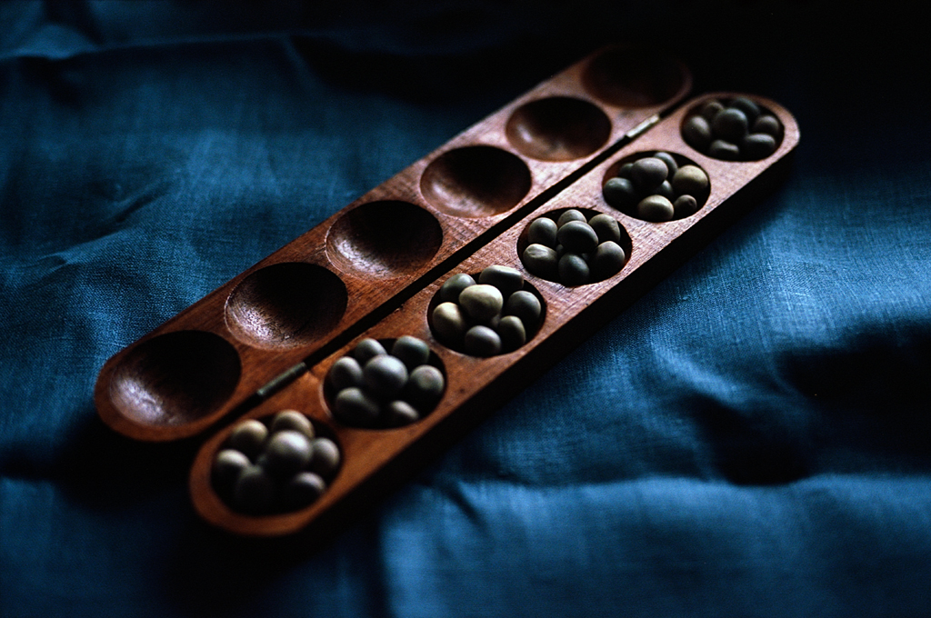 Un plateau en bois contenant des billes de différentes couleurs, sur un fond de tissu bleu.
