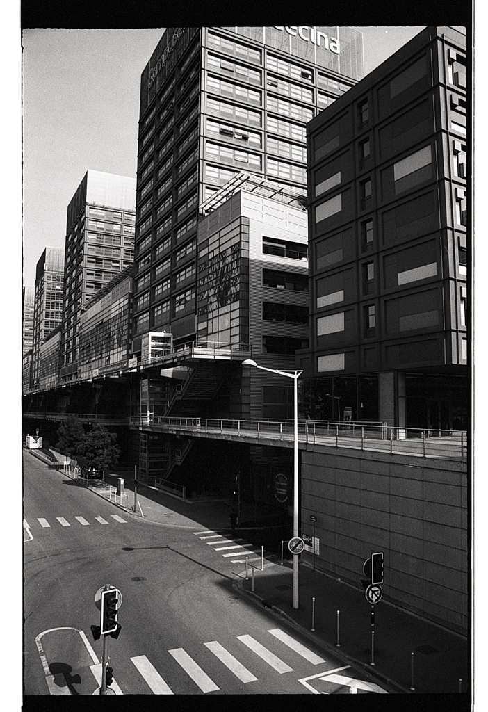 Vue en noir et blanc d'un paysage urbain avec des bâtiments modernes et une rue vide.