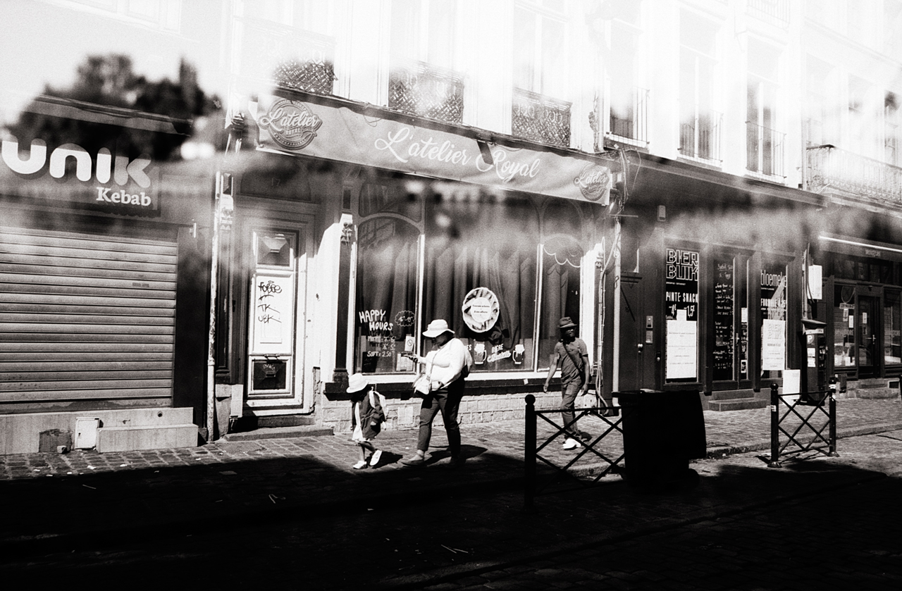Une scène de rue à Lille, montrant des passants marchant devant des boutiques avec une exposition en noir et blanc.