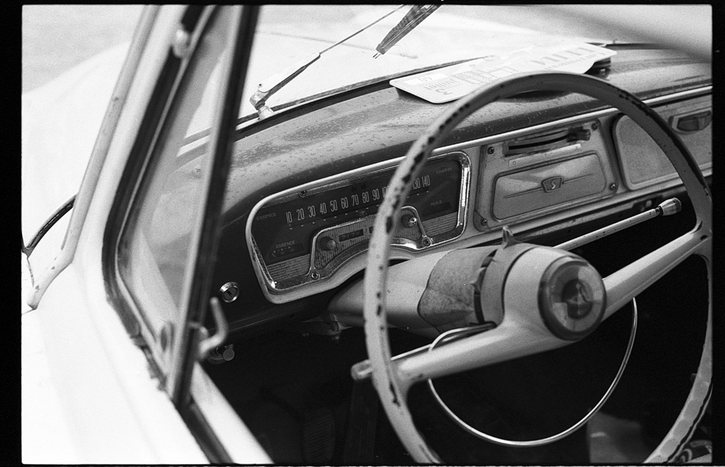 Vue rapprochée du tableau de bord d'une voiture ancienne, mettant en évidence le volant, les compteurs et la garniture vintage.