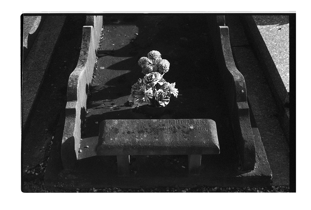 Un cimetière ancien avec une pierre tombale ornée de fleurs, capturée en noir et blanc.