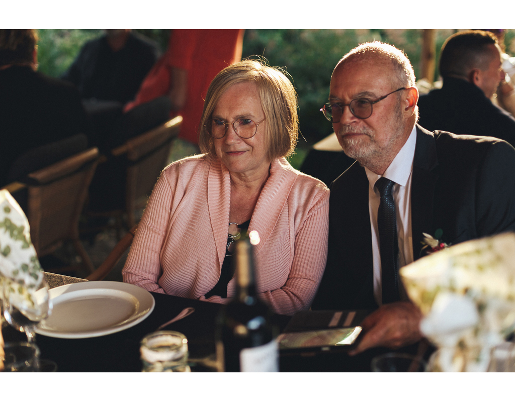 Un couple souriant assis à une table, entouré d'une ambiance conviviale, lors d'un événement social.