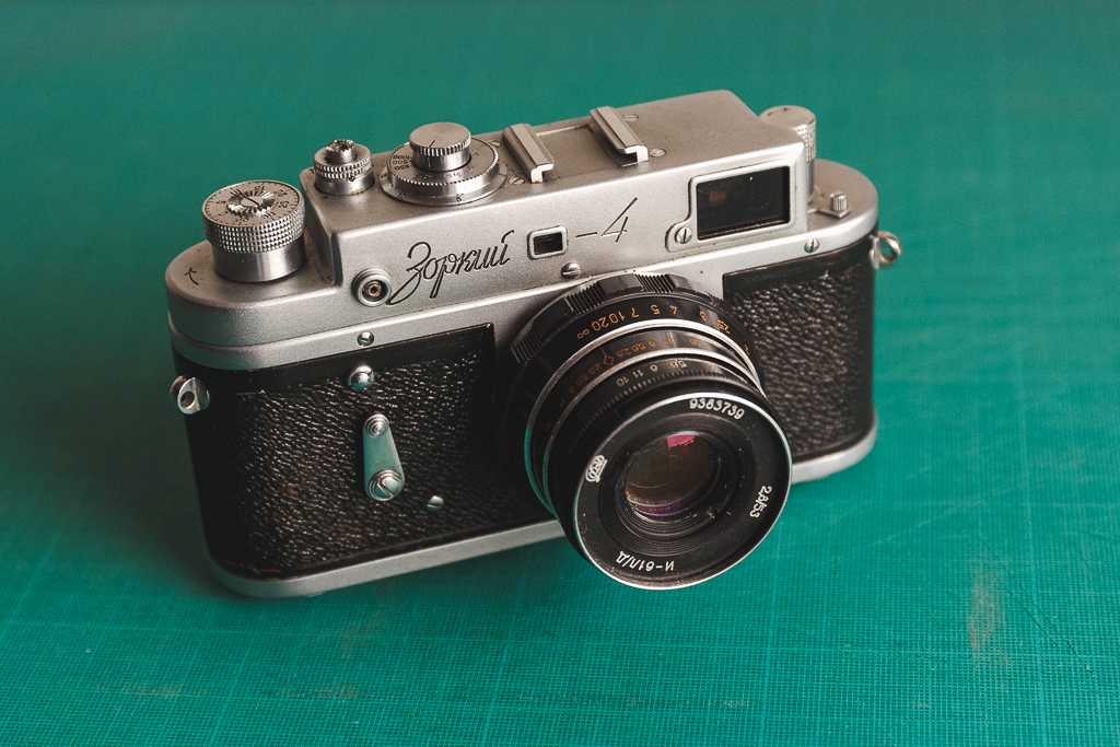 Appareil photo vintage Zorki 4 posé sur une surface verte, avec un objectif visible et des réglages manuels sur le dessus.