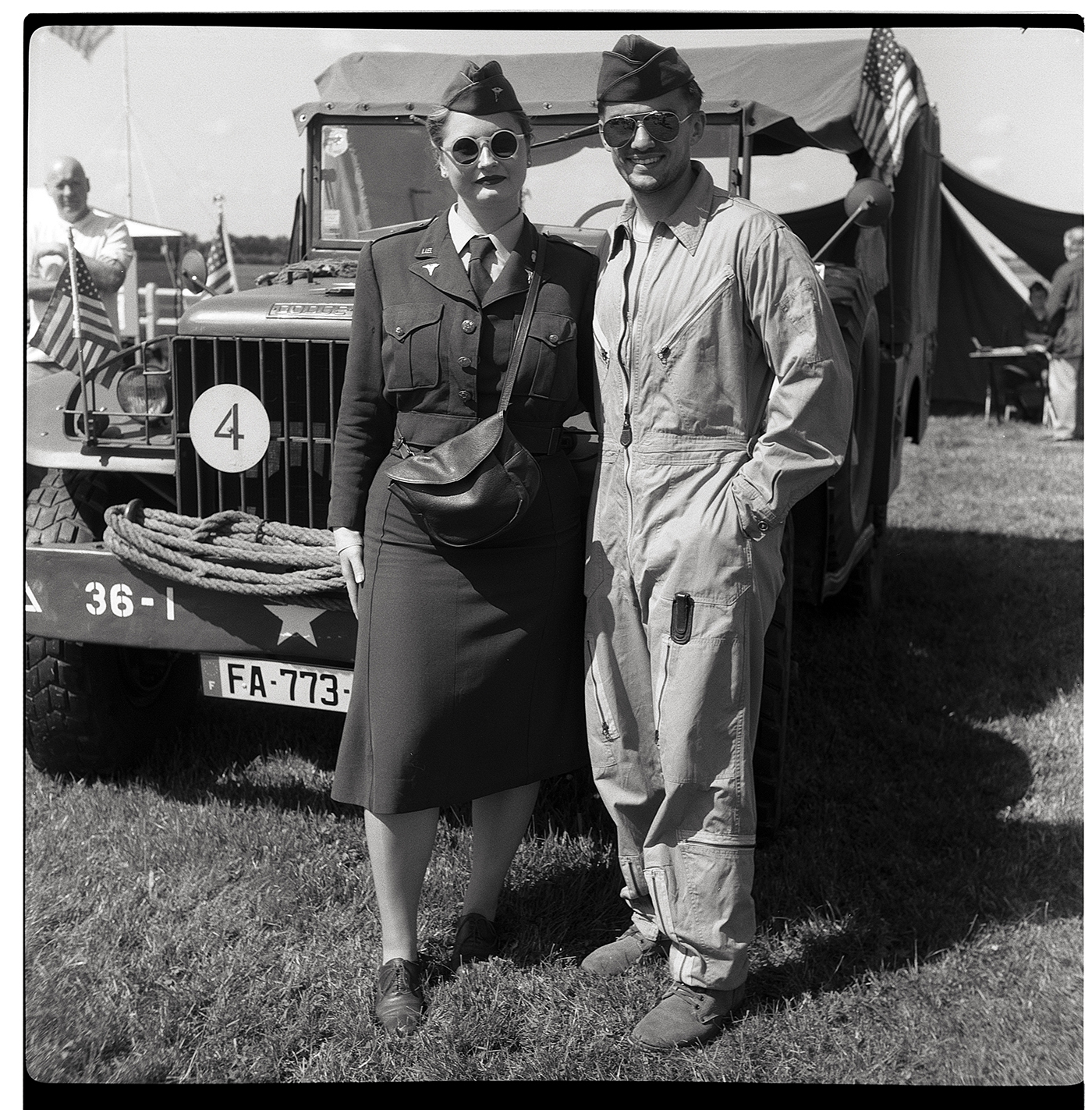 Couple en tenue militaire posant devant un véhicule militaire, lors d'un événement de reconstitution historique.