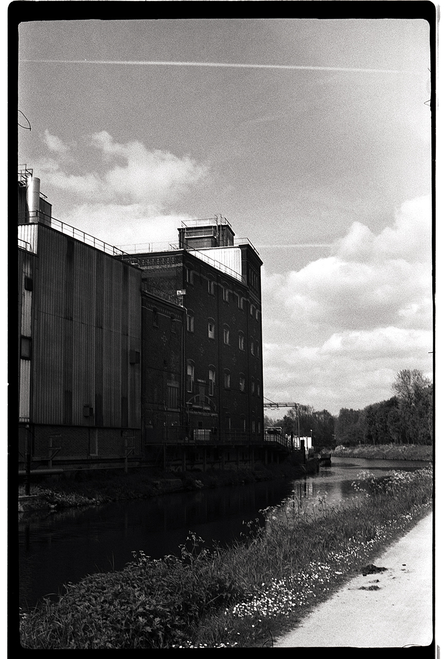 Photographie sombre noir et blanc argentique. Usine sur le bord d'un canal.