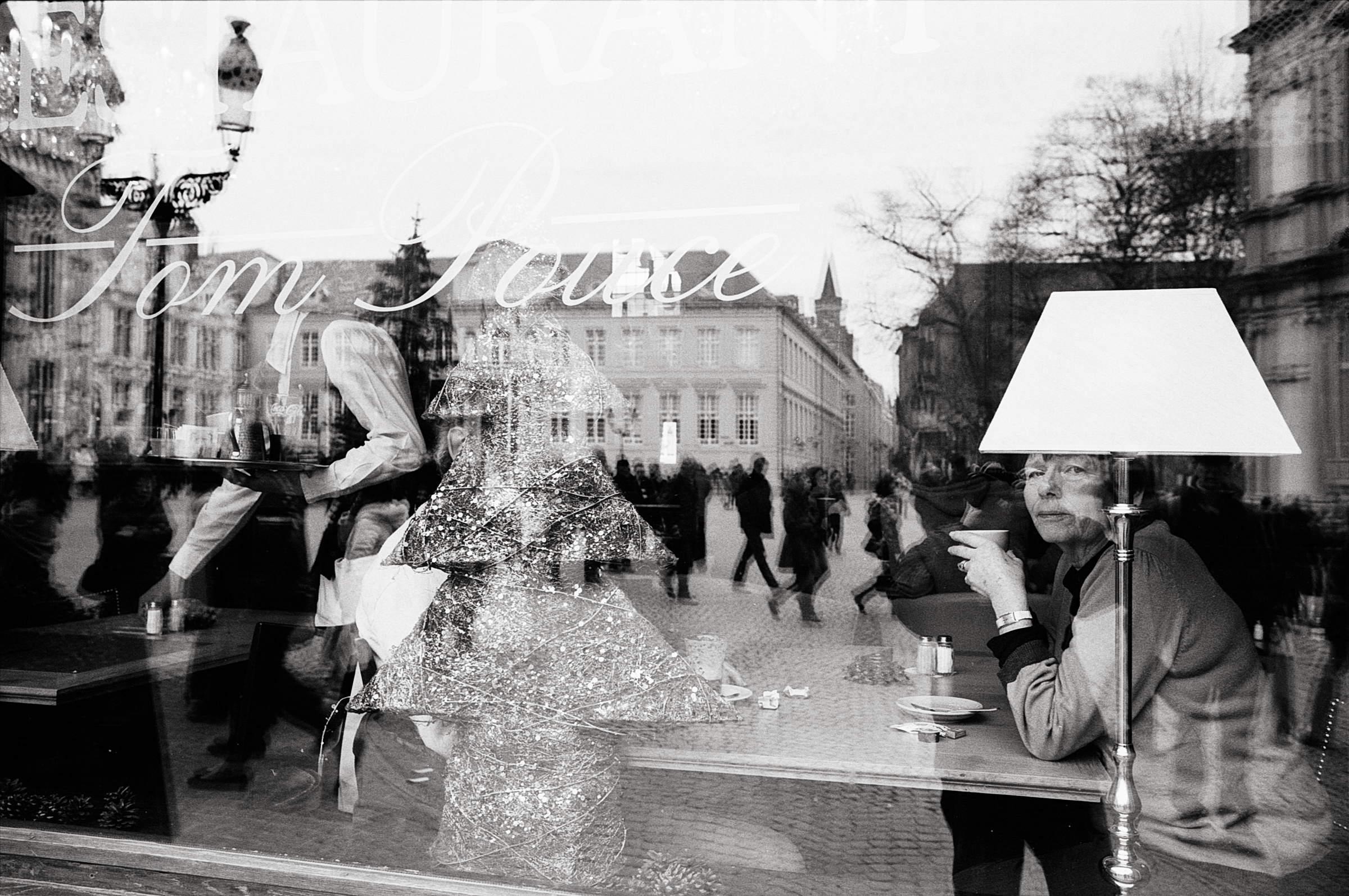 Street photography en noir et blanc argentique en Belgique. Reflets dans la vitrine d'un bar restaurant à Bruges. 